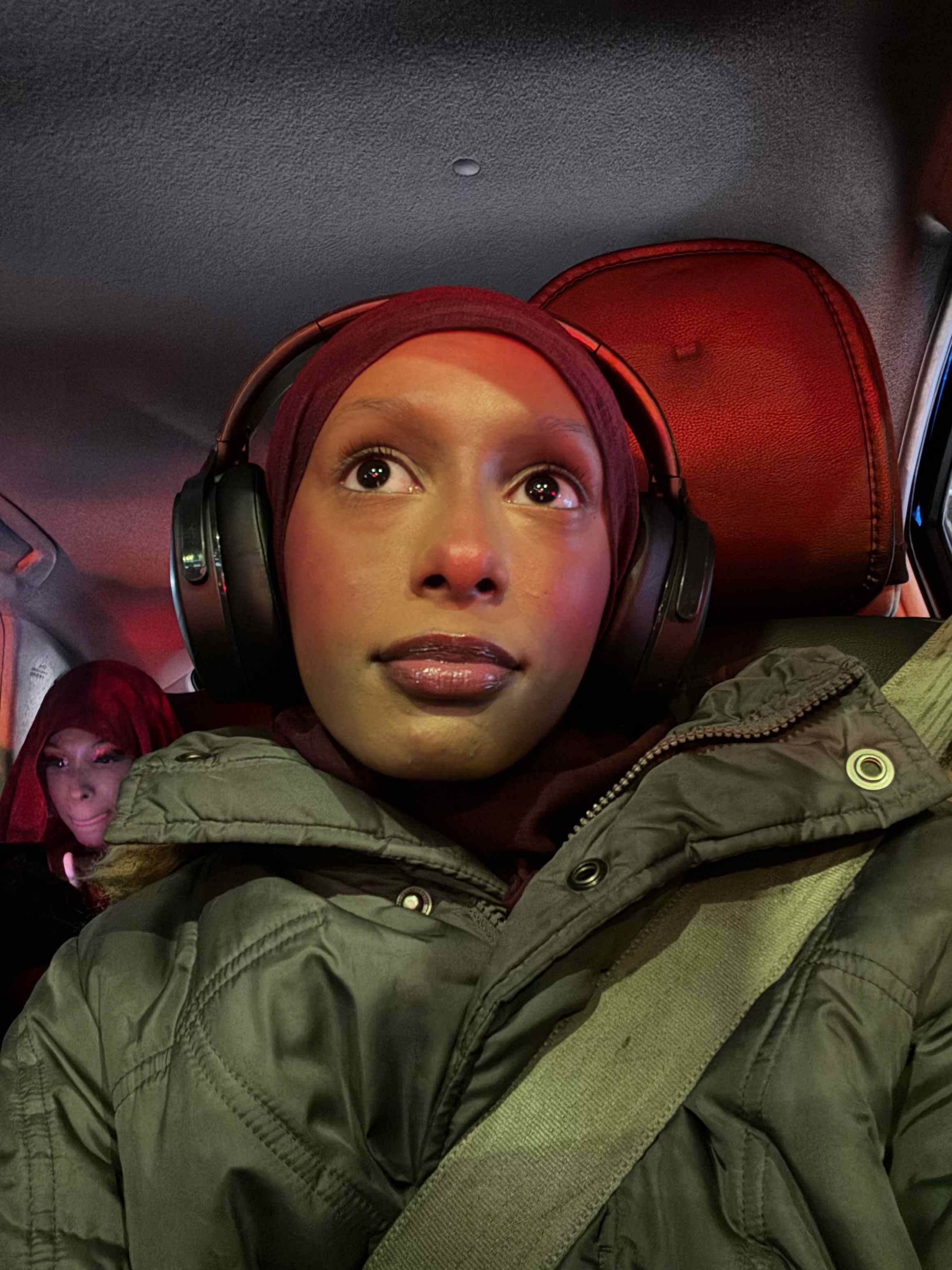 Photo of Aisha sitting in a car wearing headphones