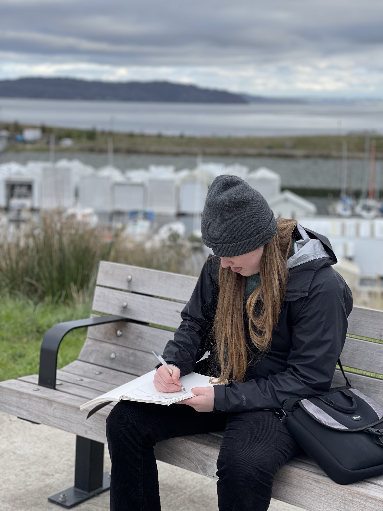 Photo of Carley sitting on a bench writing in her journal