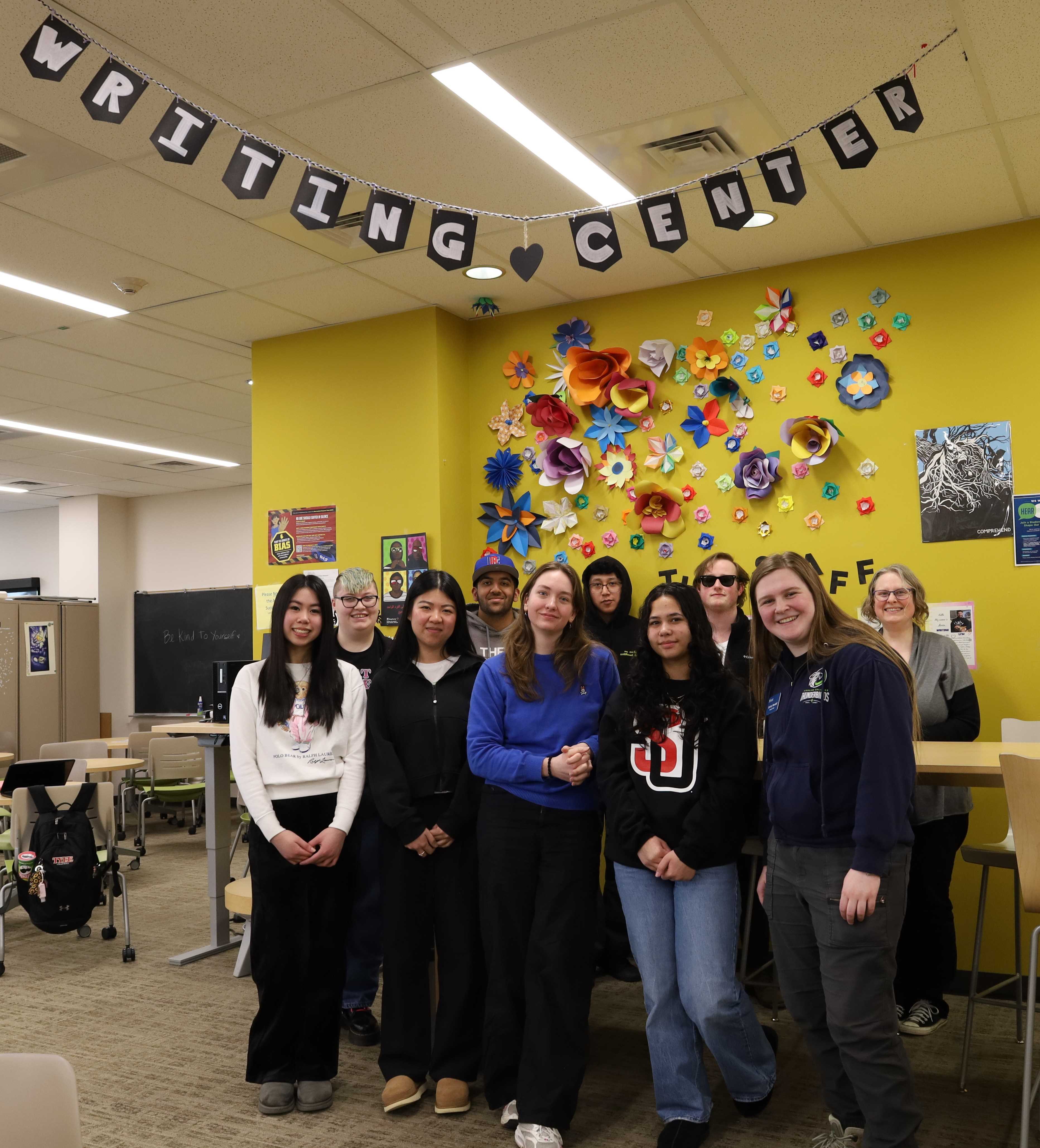 Writing Center Group Photo Photo of a diverse, multiethnic group of people standing under a sign that says writing center.